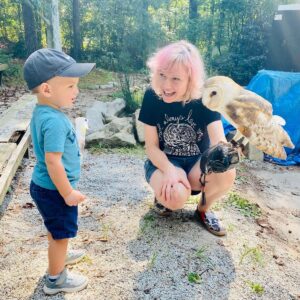 Volunteer Nan shares Boogie the barred owl with a young visitor